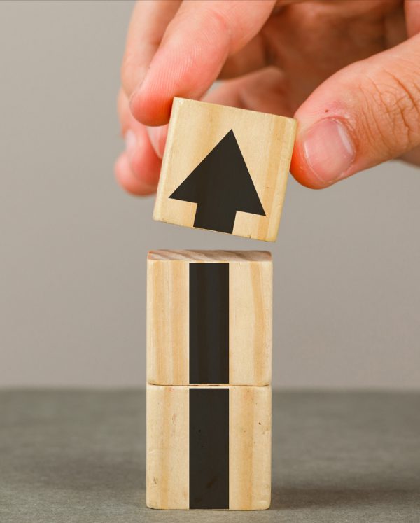 Business growth concept on grey and white background side view. hand putting wood block onto tower.